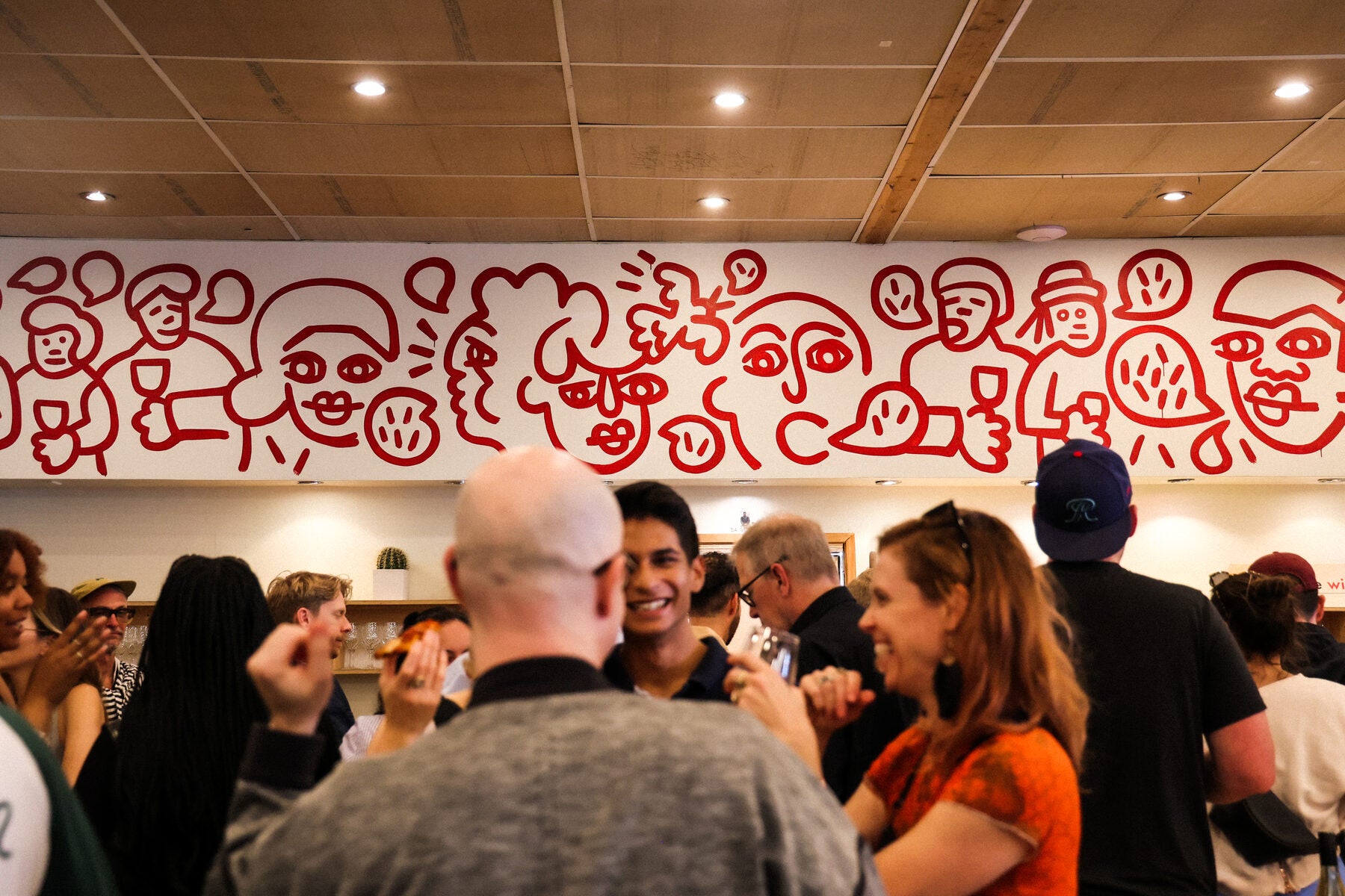 People mingling at the bar under the mural