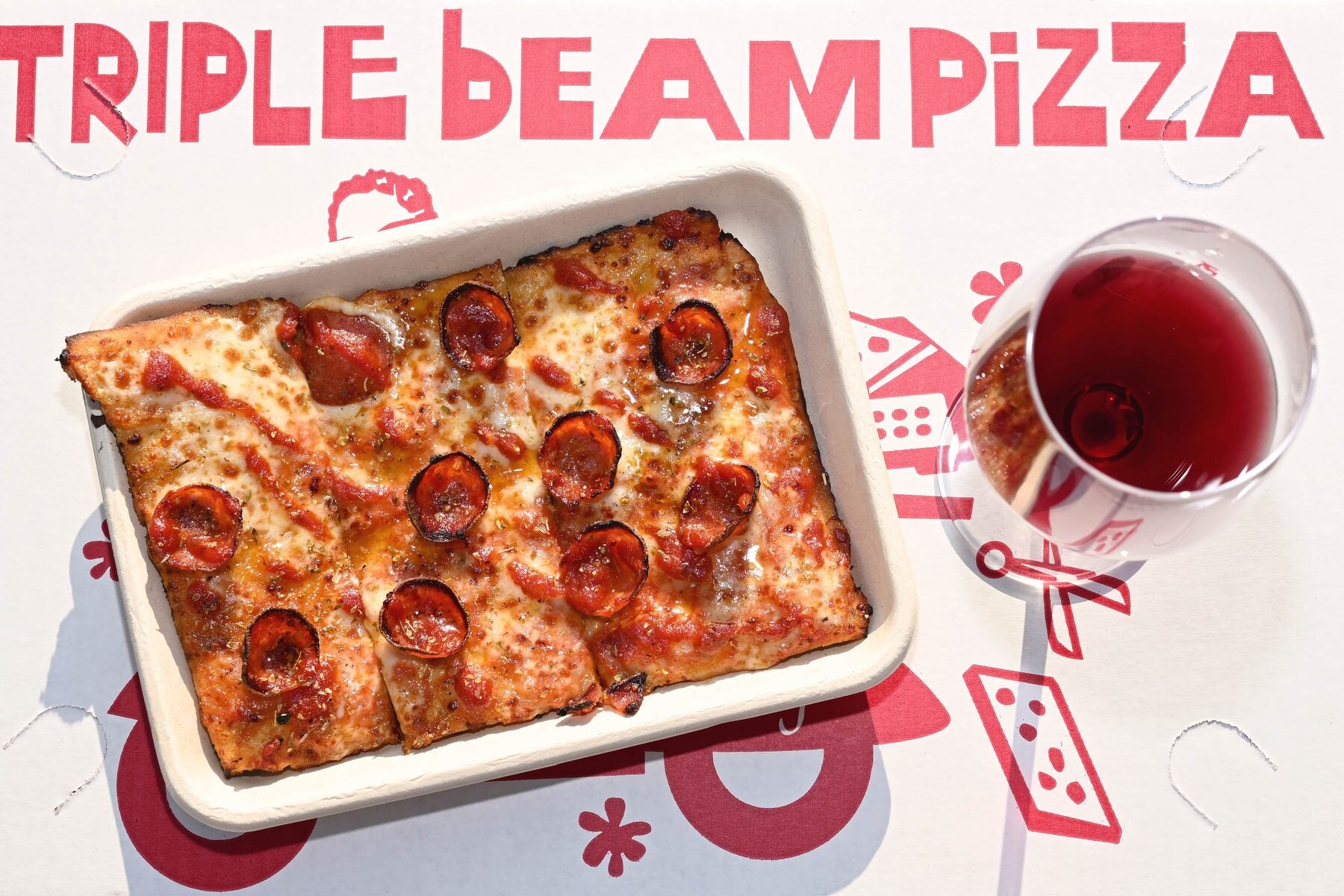 Triple Beam pizza box and a glass of red wine, overhead