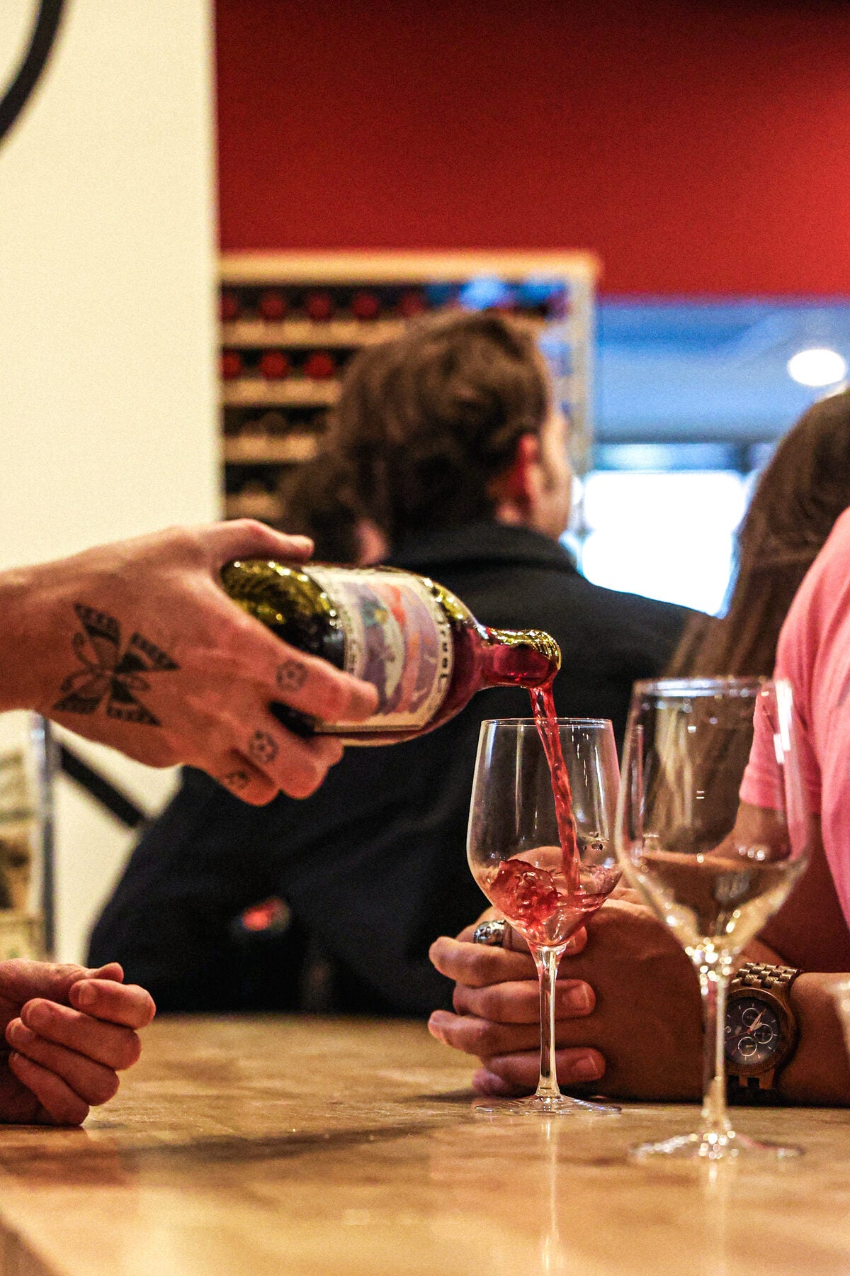 A bottle being poured into a wine glass at the bar